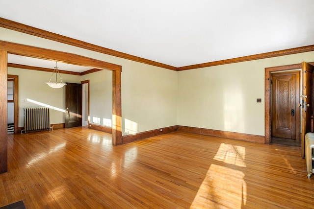 empty room featuring radiator heating unit, hardwood / wood-style flooring, and crown molding