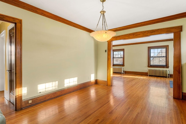 unfurnished room with hardwood / wood-style floors, radiator, and ornamental molding