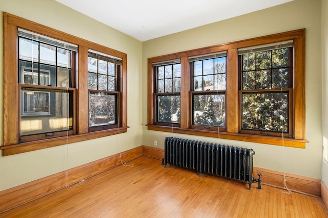 spare room featuring radiator heating unit, a healthy amount of sunlight, and light hardwood / wood-style flooring