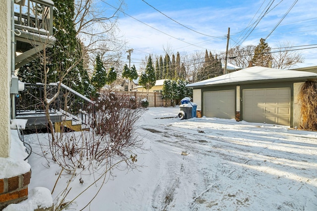 snowy yard with a garage and an outbuilding