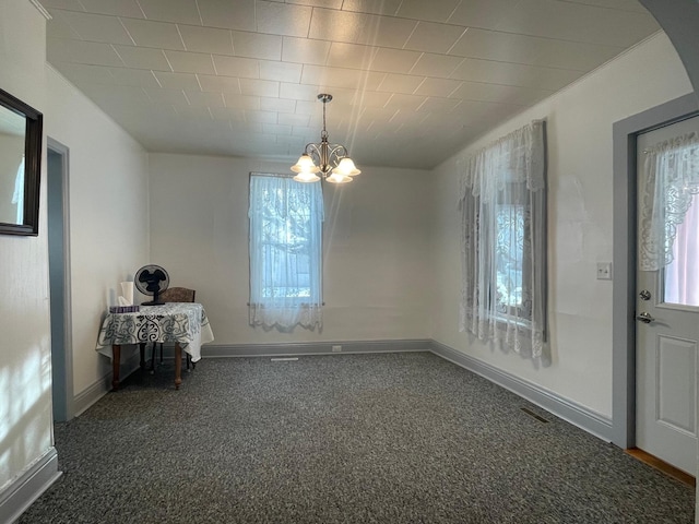 unfurnished dining area featuring dark colored carpet and a chandelier