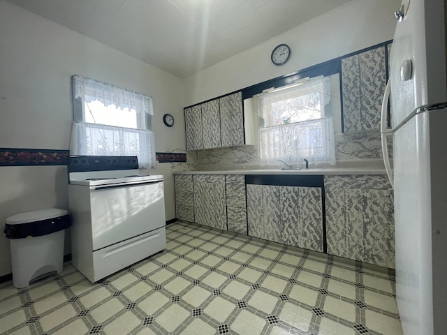 kitchen with white appliances, sink, and a wealth of natural light