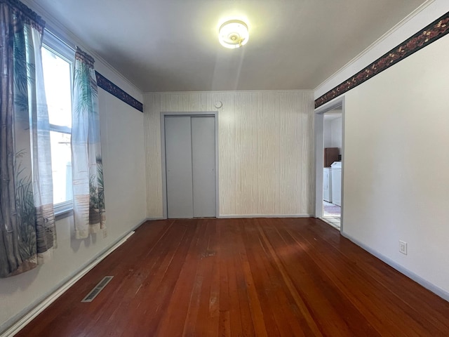 empty room with ornamental molding, dark hardwood / wood-style flooring, washer / clothes dryer, and a healthy amount of sunlight