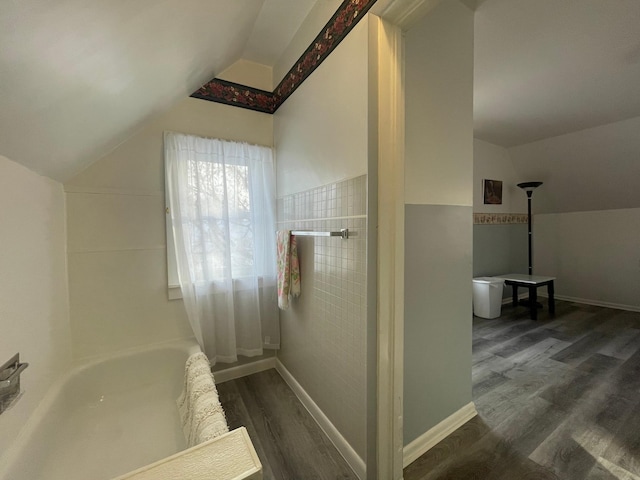 bathroom with hardwood / wood-style flooring, vaulted ceiling, and walk in shower