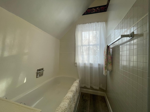 bathroom featuring a tub to relax in, lofted ceiling, and hardwood / wood-style flooring