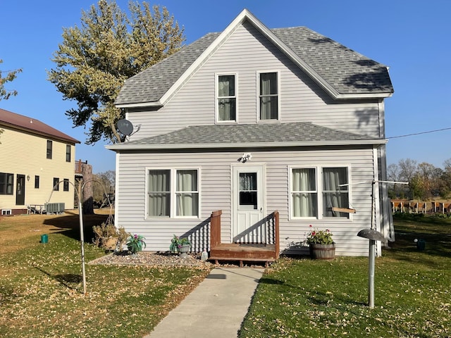 view of front of home with central AC unit and a front yard