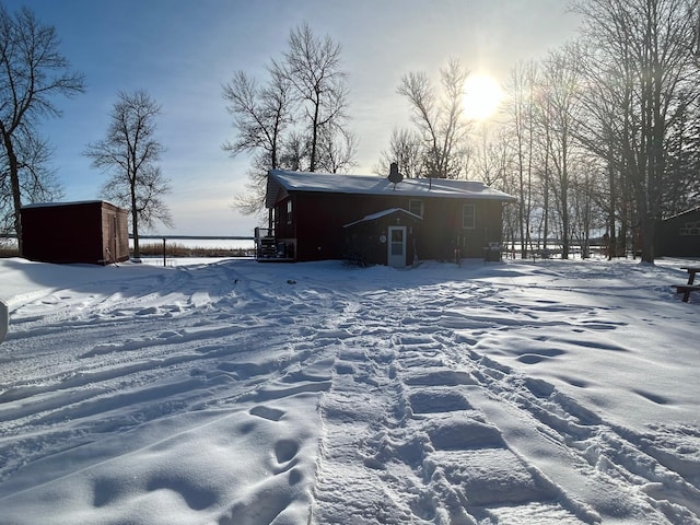 snow covered back of property featuring a storage unit