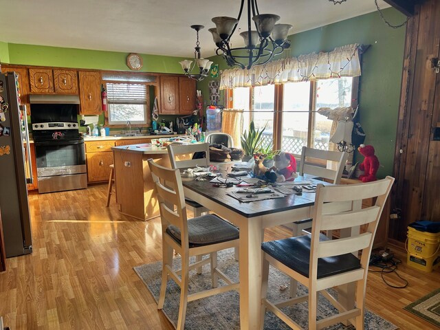 dining area with sink, light hardwood / wood-style flooring, and a chandelier