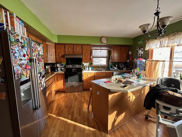 kitchen with a center island, sink, light hardwood / wood-style floors, stainless steel appliances, and a chandelier