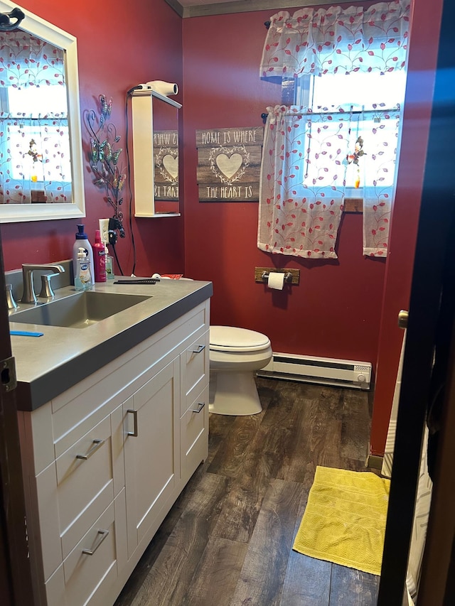 bathroom featuring vanity, toilet, wood-type flooring, and a baseboard heating unit