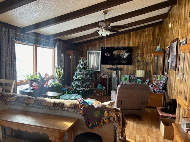 living room with hardwood / wood-style floors, vaulted ceiling with beams, ceiling fan, and wooden walls