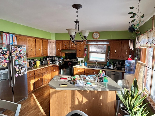 kitchen with stainless steel appliances, sink, wood-type flooring, a chandelier, and a kitchen island