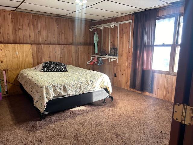 bedroom featuring carpet flooring, a paneled ceiling, and wood walls