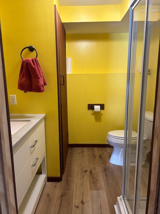 19162 Coho Loop NE, Blackduck, MN 56647 - bathroom with a shower stall, vanity, toilet, baseboards, and wood finished floors