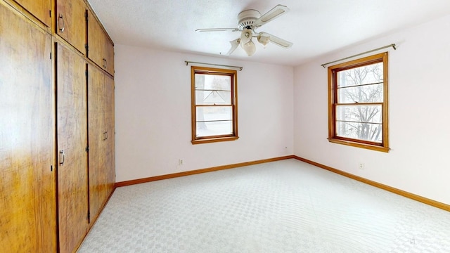 unfurnished bedroom featuring light carpet, a closet, multiple windows, and ceiling fan