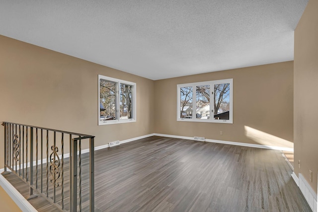 empty room featuring a textured ceiling and dark hardwood / wood-style floors