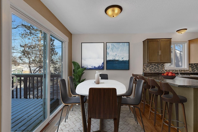 dining room featuring sink, a textured ceiling, and light hardwood / wood-style flooring