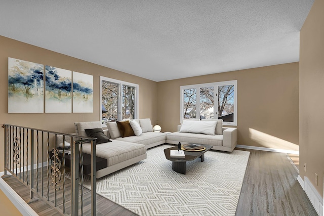 living area with baseboards, a textured ceiling, wood finished floors, and visible vents