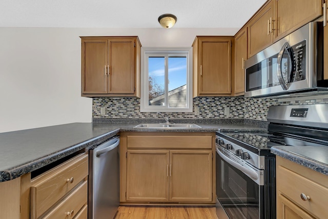 kitchen with a sink, appliances with stainless steel finishes, backsplash, and dark countertops