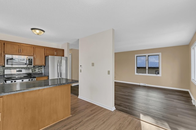 kitchen with dark countertops, baseboards, stainless steel appliances, and dark wood finished floors