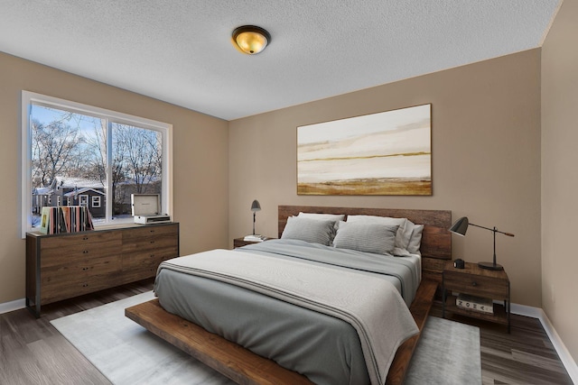 bedroom with baseboards, a textured ceiling, and wood finished floors