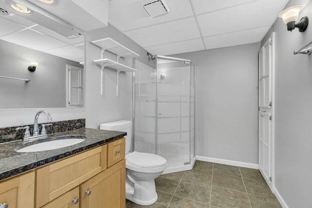 full bathroom featuring toilet, baseboards, a drop ceiling, and a shower stall