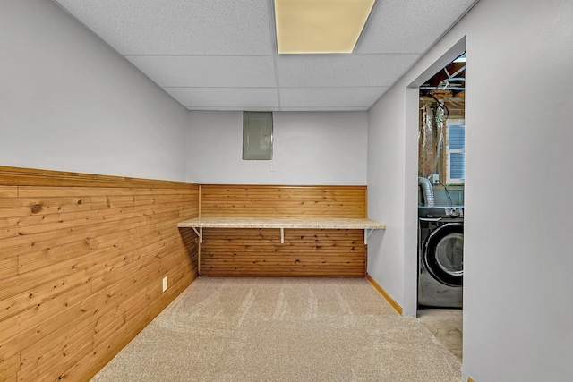 interior space featuring electric panel, a paneled ceiling, wooden walls, washer / dryer, and carpet flooring