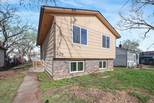 back of property featuring a lawn and brick siding