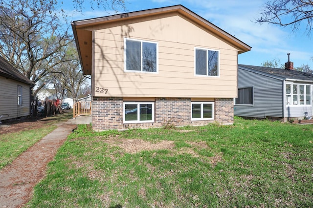 rear view of house with a lawn and brick siding