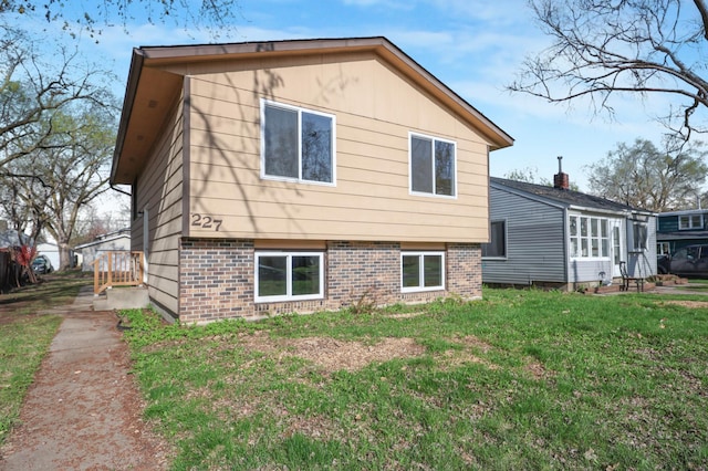 rear view of property featuring a lawn and brick siding