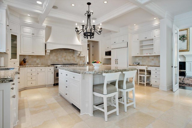 kitchen with pendant lighting, built in appliances, light stone countertops, a center island with sink, and custom exhaust hood