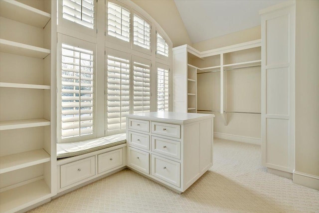 spacious closet with light carpet and vaulted ceiling