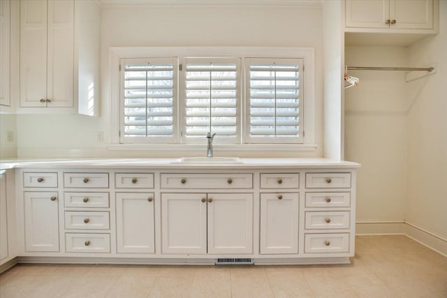 interior space featuring white cabinetry, light tile patterned flooring, and sink