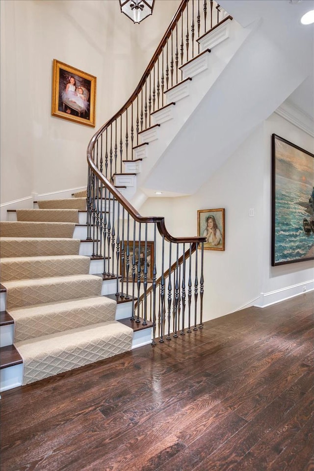 stairs with hardwood / wood-style flooring, ornamental molding, and a high ceiling