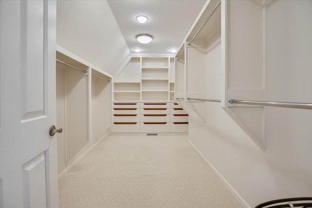 spacious closet with lofted ceiling and light carpet