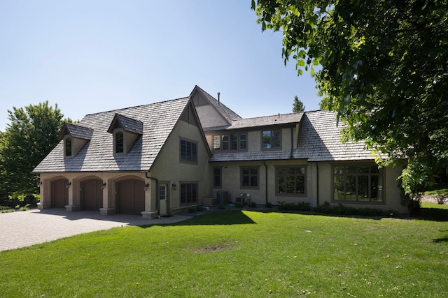 view of front of house with a garage, central air condition unit, and a front lawn