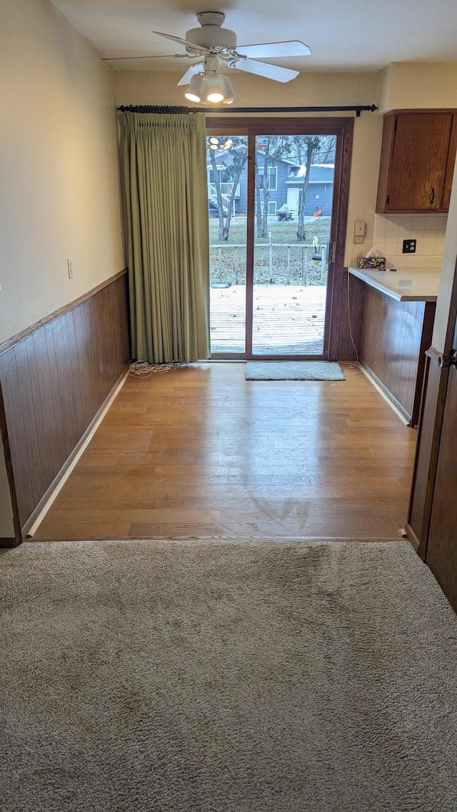 interior space featuring ceiling fan, light hardwood / wood-style flooring, and wood walls