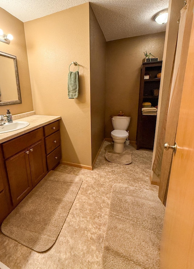 bathroom with vanity, a textured ceiling, and toilet