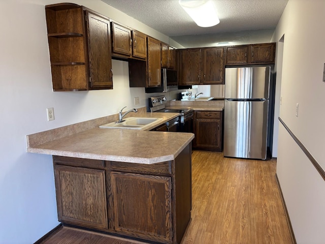 kitchen with stainless steel appliances, kitchen peninsula, sink, and dark brown cabinets