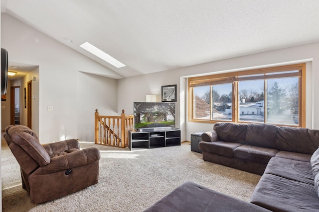 carpeted living room featuring a skylight and high vaulted ceiling