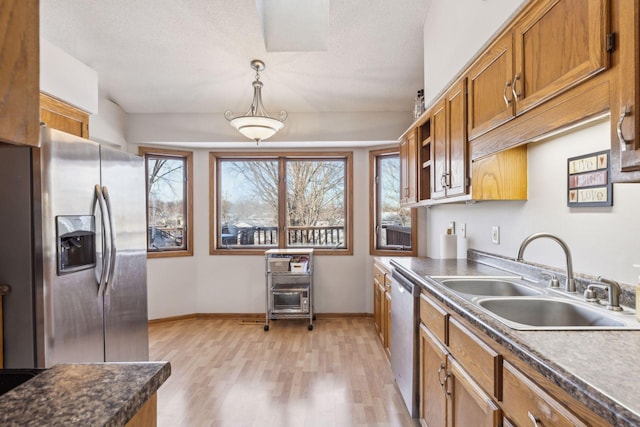 kitchen featuring sink, a textured ceiling, decorative light fixtures, appliances with stainless steel finishes, and light wood-type flooring