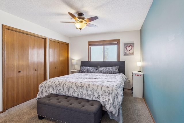 bedroom with ceiling fan, carpet floors, a textured ceiling, and multiple closets