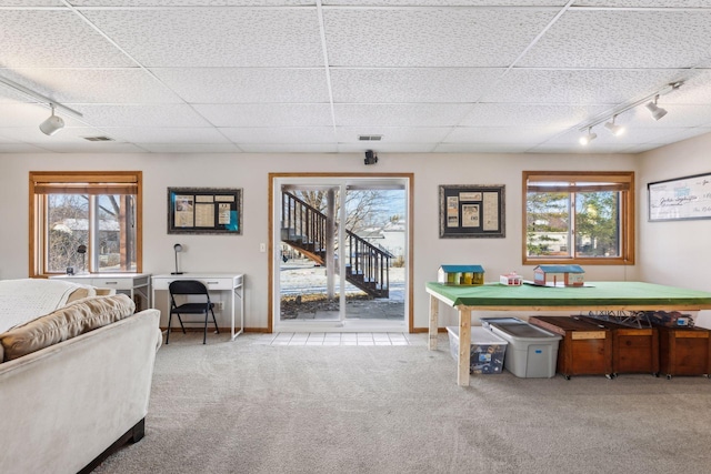 carpeted dining space with a drop ceiling, a healthy amount of sunlight, and track lighting