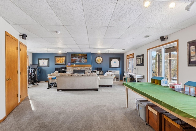 living room with a fireplace, a paneled ceiling, and light colored carpet