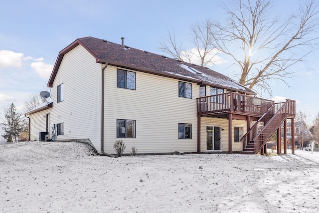 snow covered property with a wooden deck and central AC