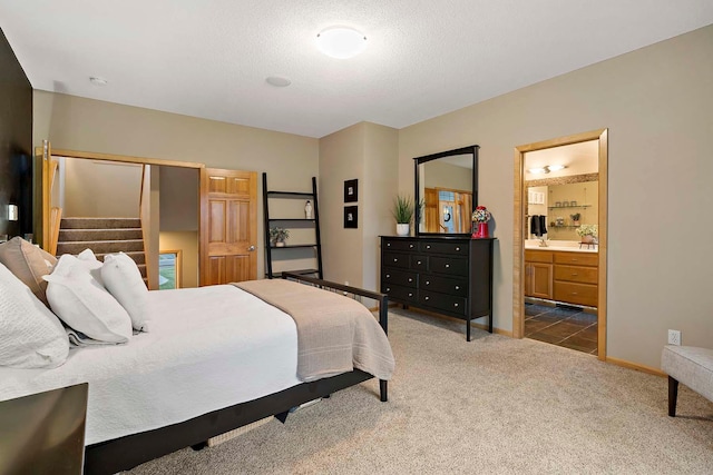 bedroom featuring dark colored carpet, a textured ceiling, and ensuite bathroom