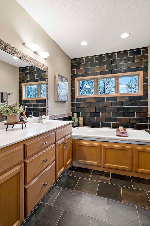 bathroom featuring decorative backsplash, a bathtub, vanity, and tile walls