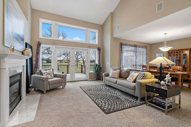 carpeted living room featuring a high end fireplace, high vaulted ceiling, and french doors