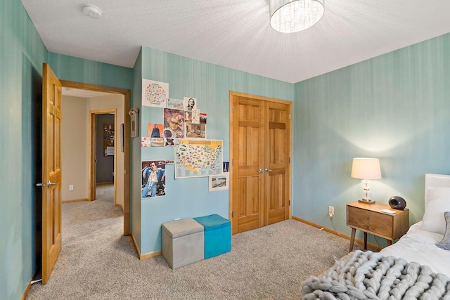 carpeted bedroom featuring a chandelier, a textured ceiling, and a closet