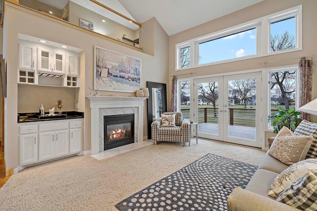 living room with a premium fireplace, french doors, high vaulted ceiling, and light colored carpet